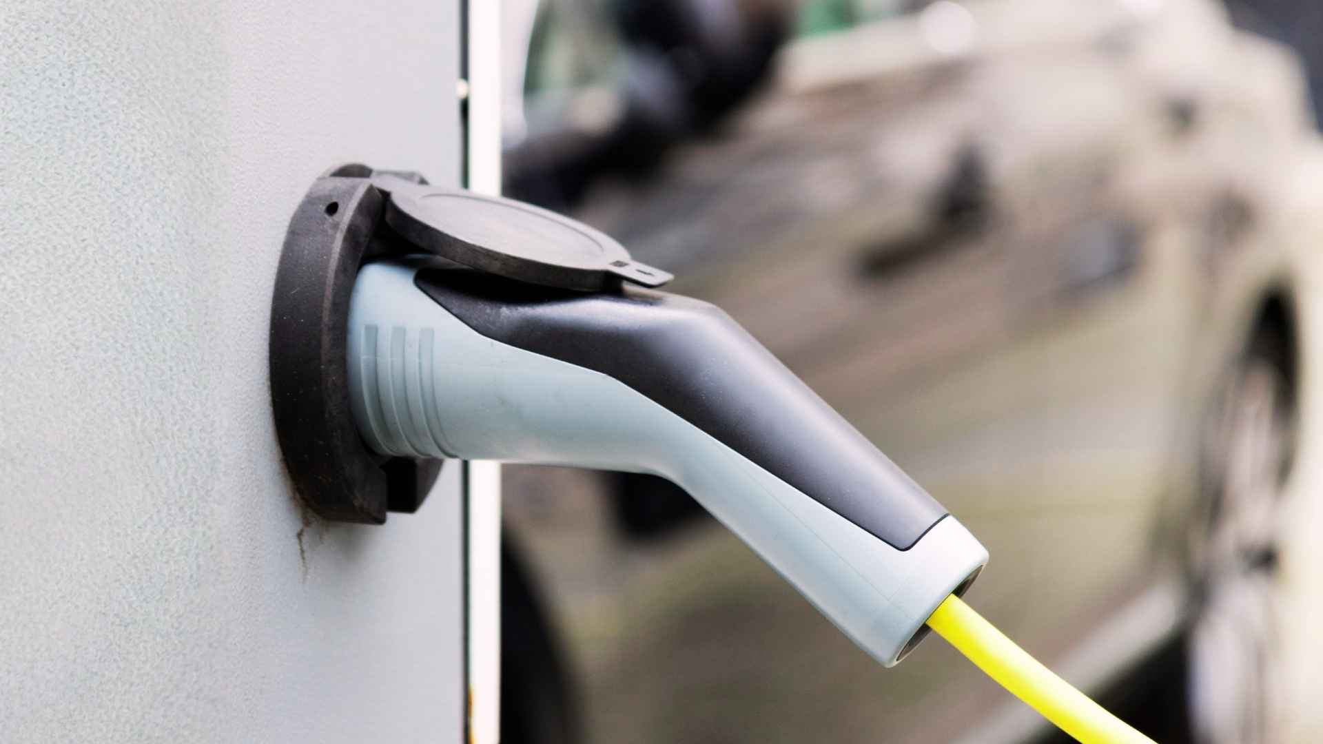 Ladestecker eines Elektrofahrzeugs mit angeschlossenem gelbem Ladekabel